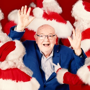 Father Bob surrounded by many Santa Claus'