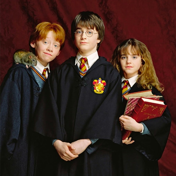 Harry, Hermione and Ron are posing for the camera in their robes with Scabbers the rat on Ron's right shoulder