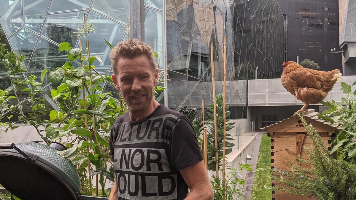 Joost Bakker on the deck of Future Food Systems with Fed Square behind him and a chicken behind his left side