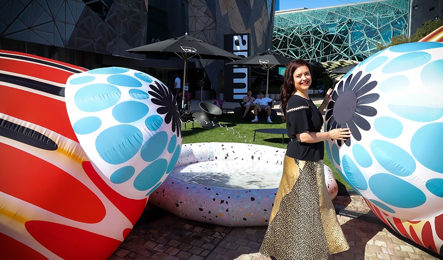 Lyndal from ENESS is standing next to an inflatable koi fish at Fed Square as part of Cupid's Koi Garden