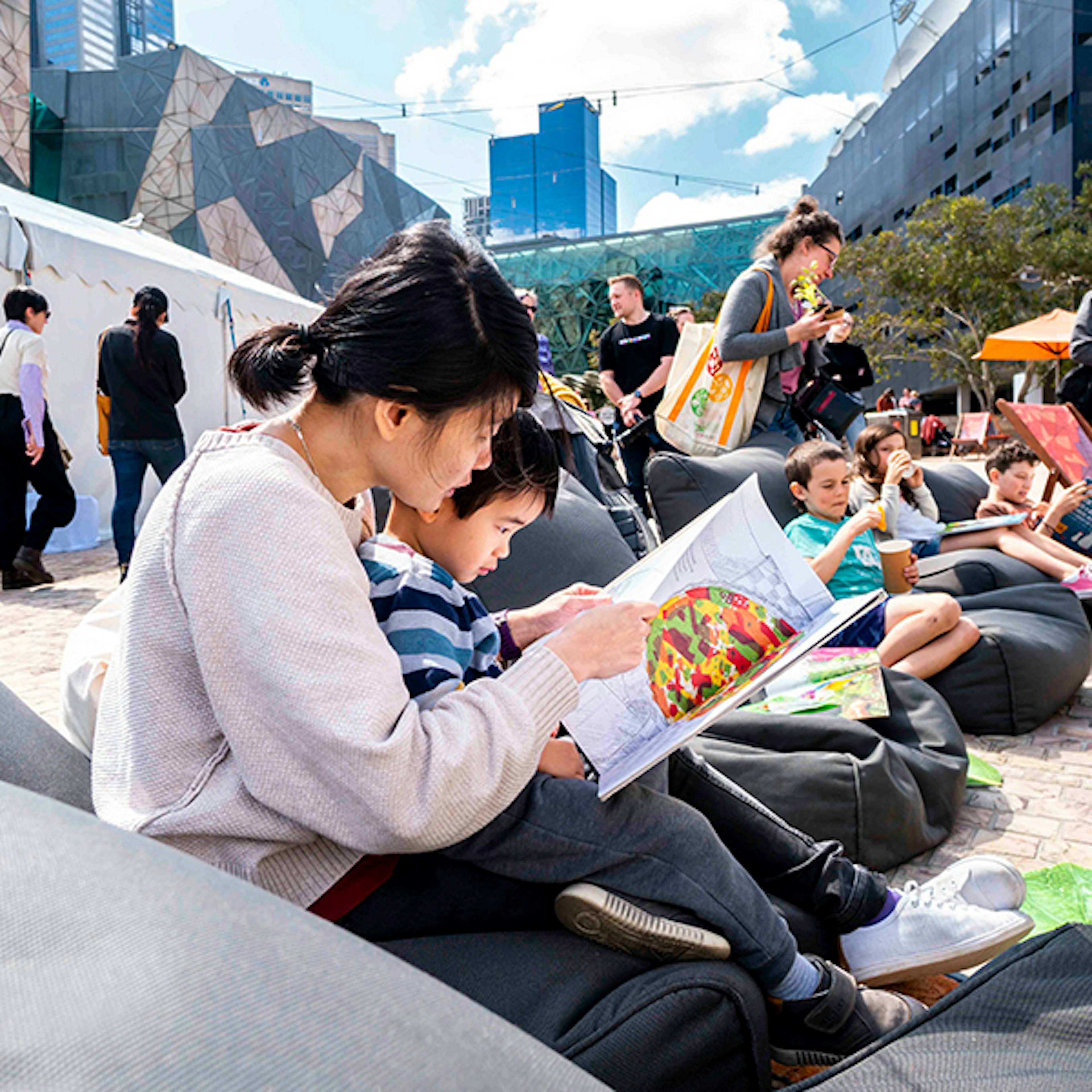 A child sitting on their parent's lap reading a book at the Little Food Festival