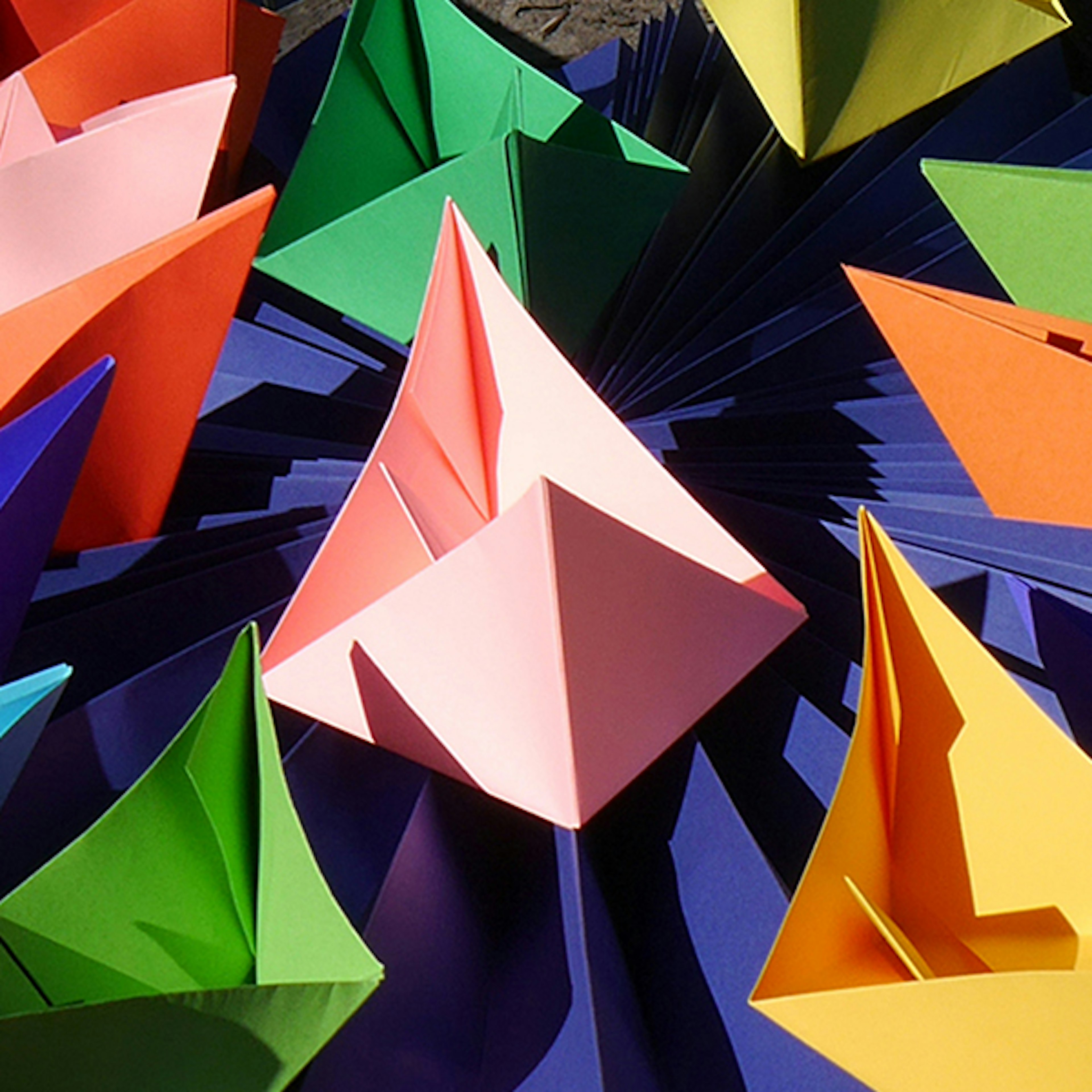 A photo of paper origami boats of varying different colours