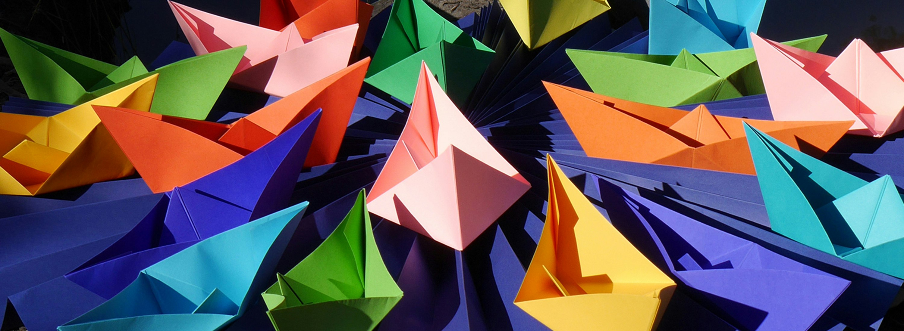A photo of paper origami boats of varying different colours
