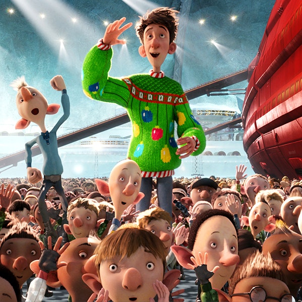 A still from Arthur Christmas of Arthur standing in a crowd of people wearing a green Christmas jumper