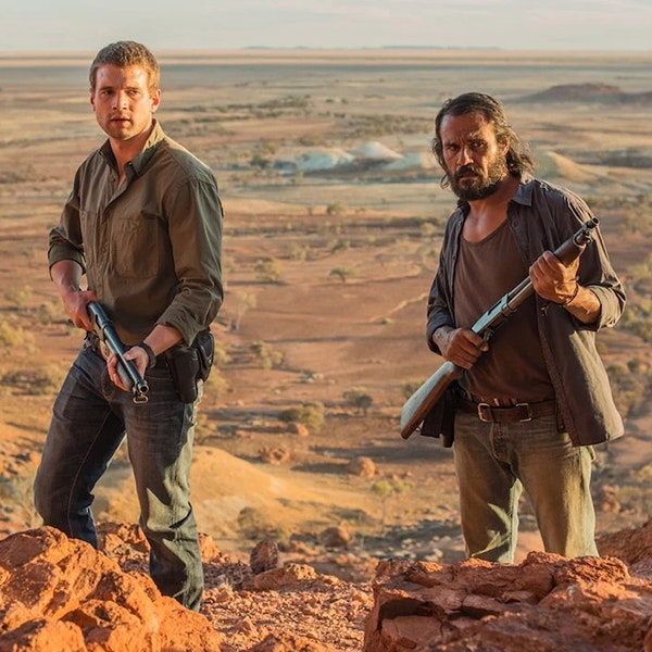 Aaron Pederson and his partner are holding guns looking towards the camera in the Australian outback in the movie Goldstone