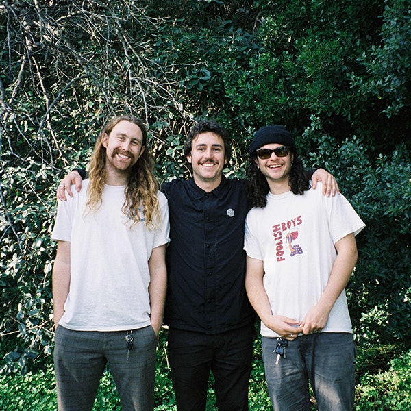 A photo of the three members of The Grogans smiling at the camera