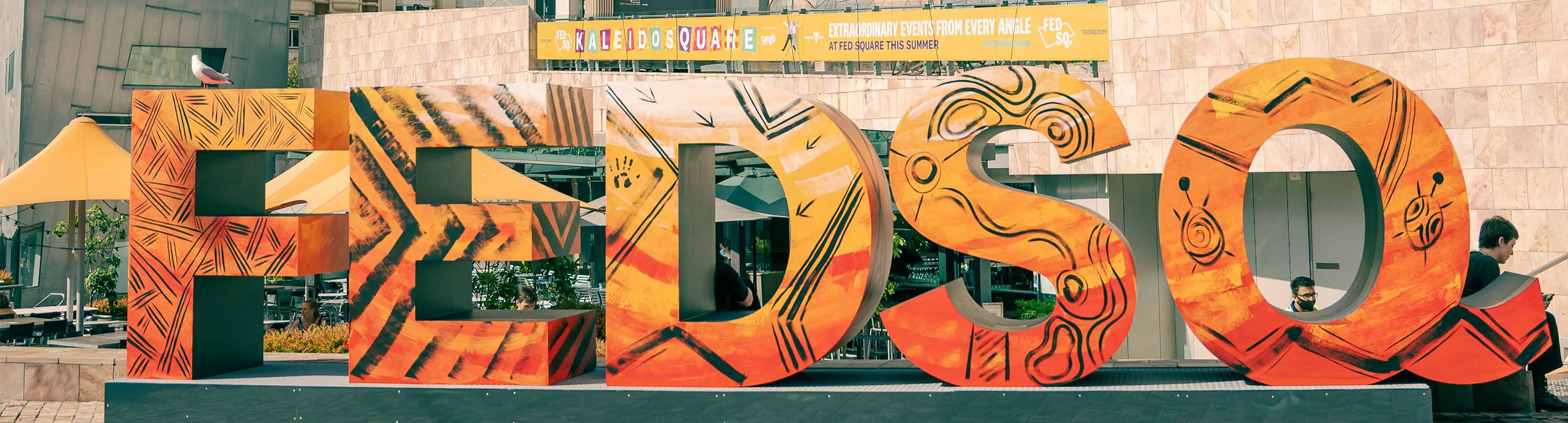 The Fed Square letters have been painted in a yellow and orange colour depicting the Creator spirit, Bunjil by First Nations artist Robert Michael Young