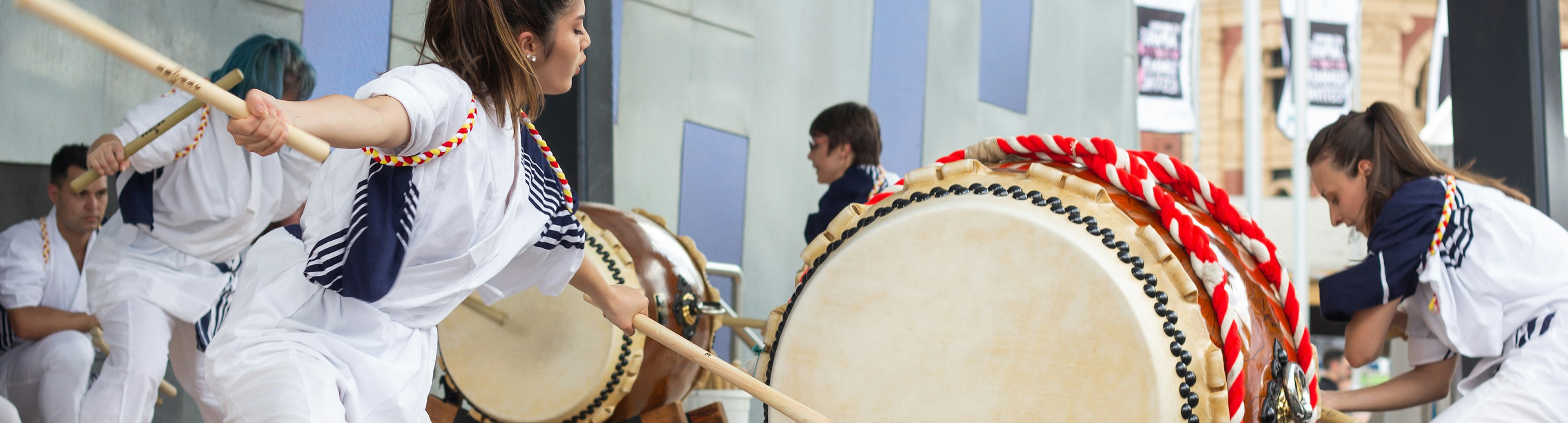 People on stage at Fed Square playing large drums for the Melbourne Japanese Summer Festival