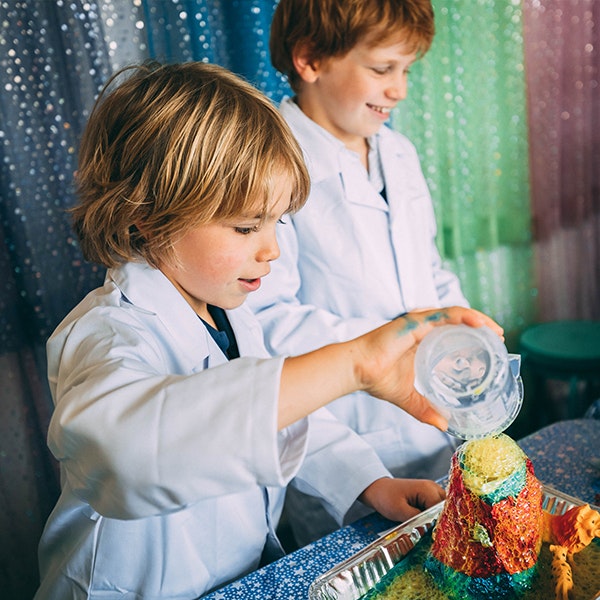 Two kids in lab coats doing an experiment in the Chemical Reactions Fizz Kidz workshop