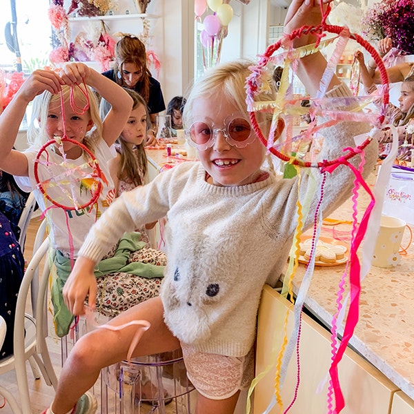 Two kids holding up dream catchers that they created in the Glitter and Shine Fizz Kidz workshop
