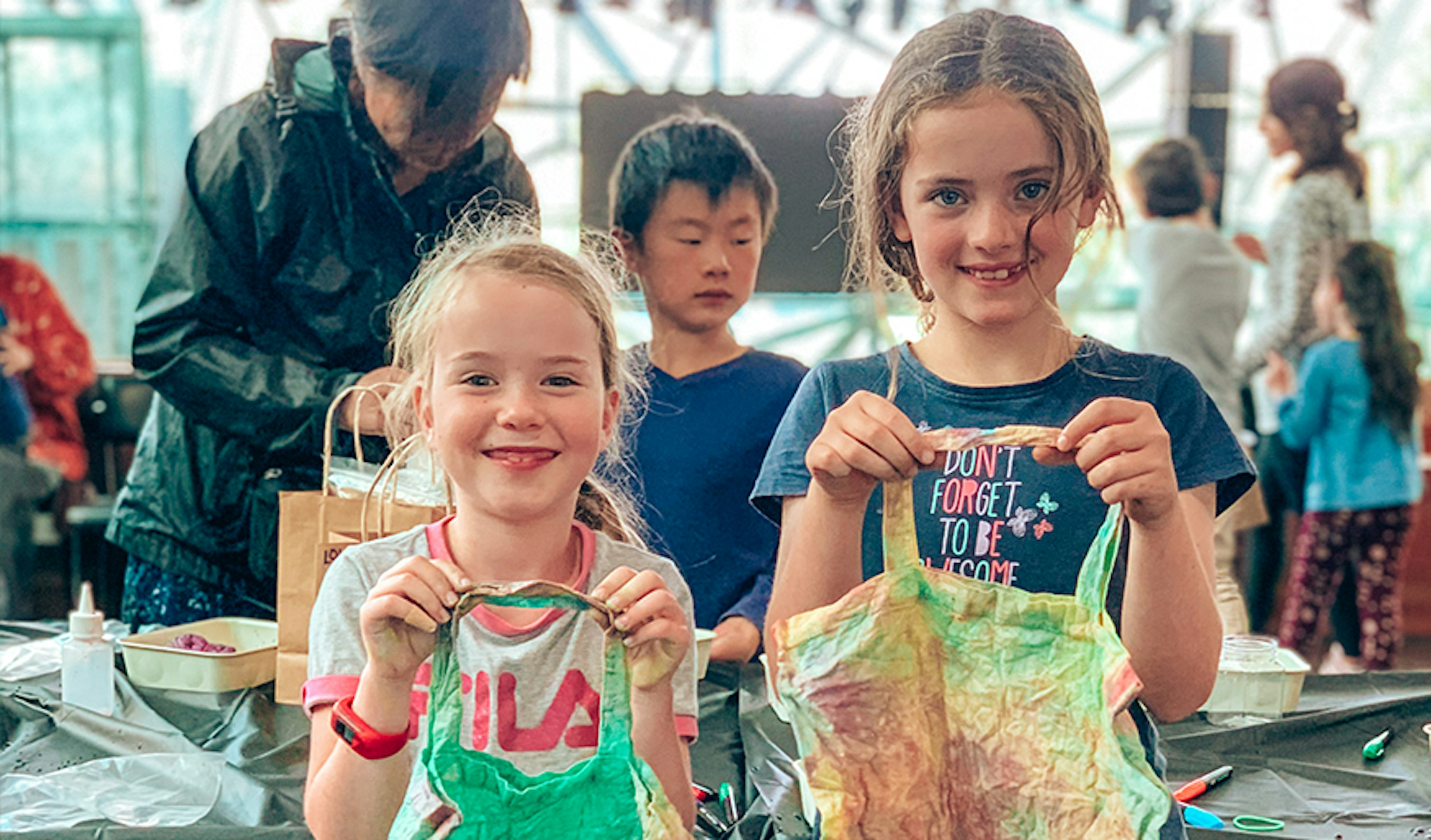 Two kids holding up tie dye aprons from a workshop at Fed Square during the school holidays