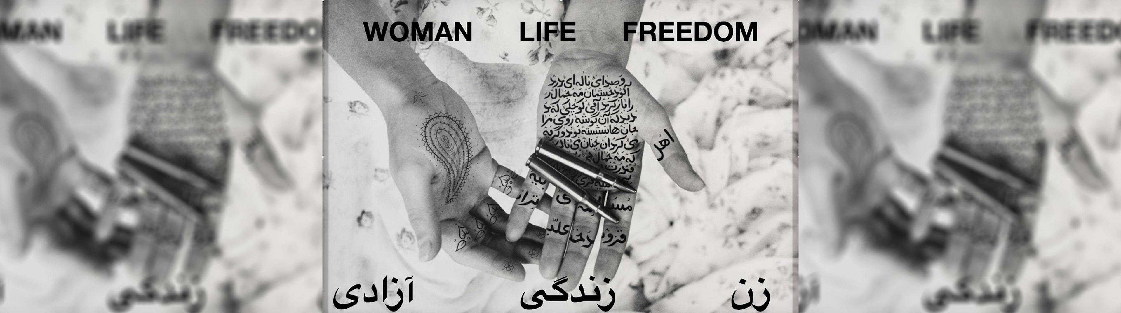 A black and white image of a person hands their left had is holding two bullets and there is Arabic writing on the palm of the hand, the right had is wresting next to the left hand palm up with henna on it