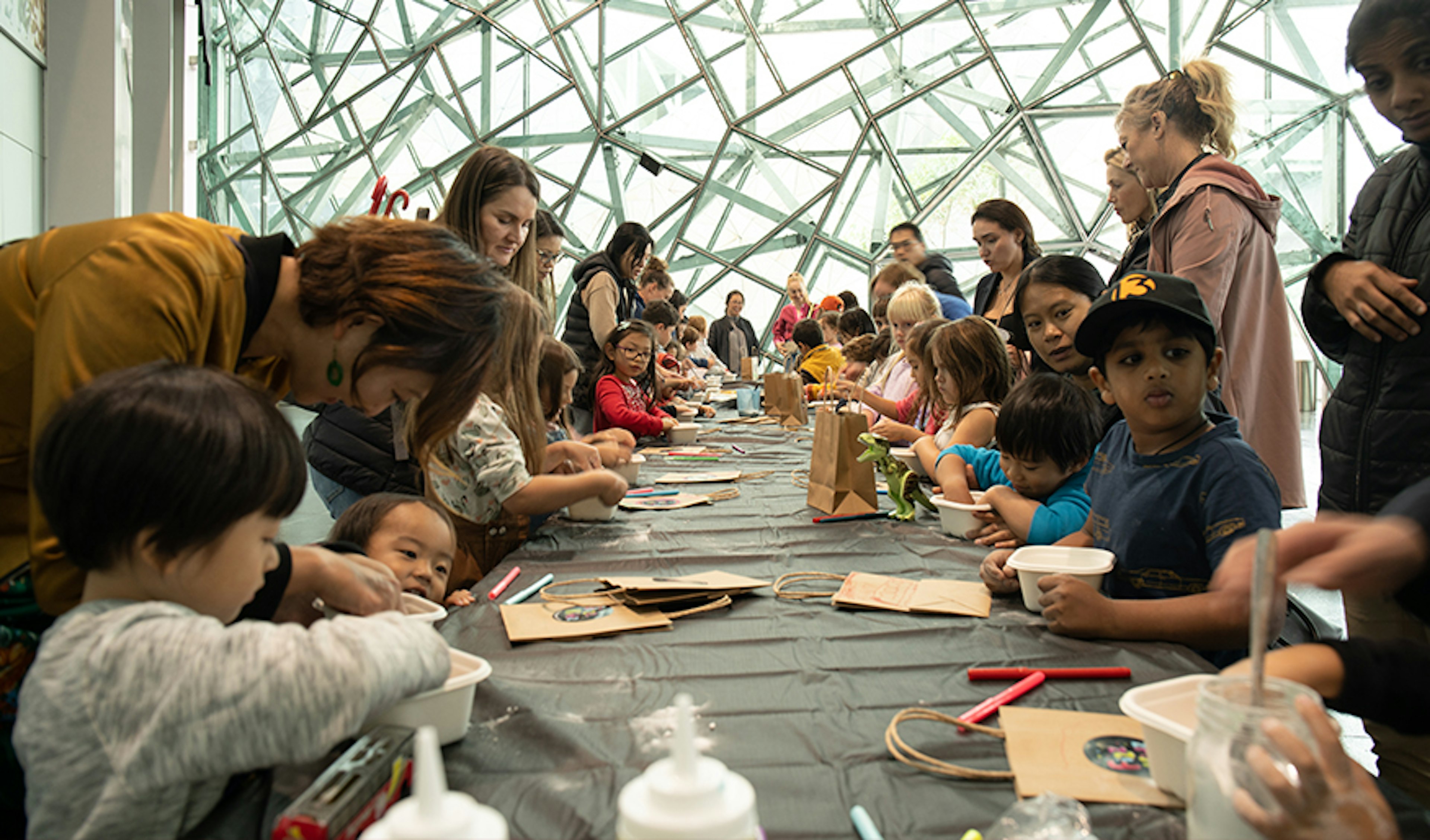 Kids and parents at a long table for a craft workshop with Fizz Kids