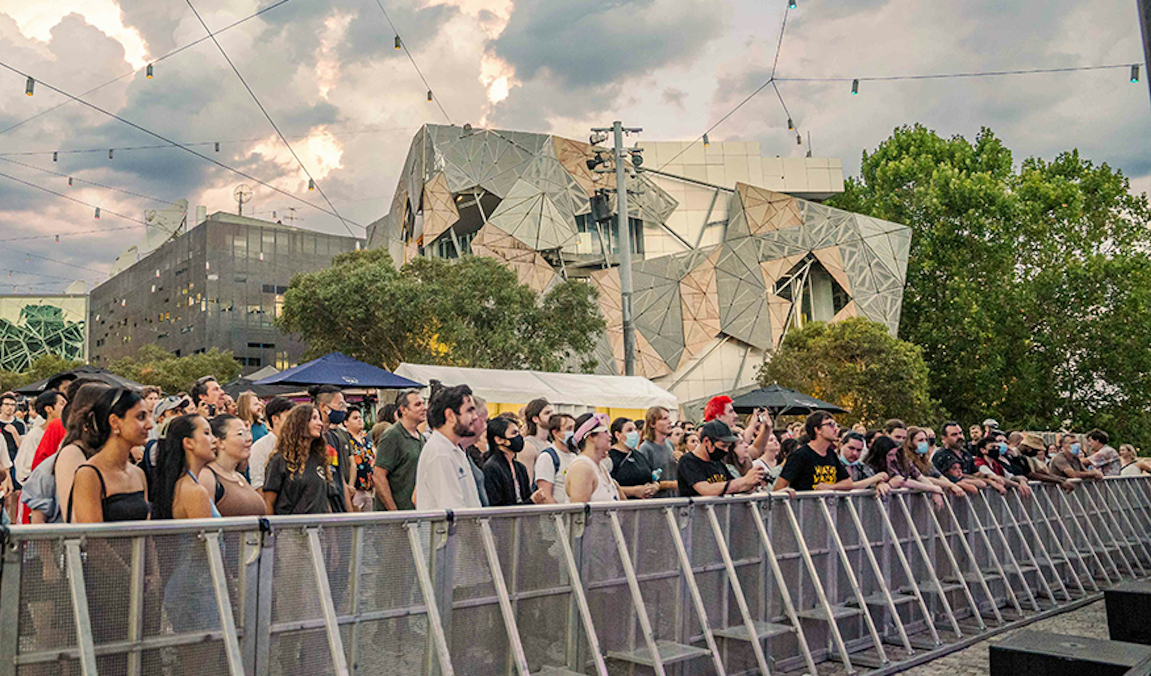 A crowd of people are watching a concert at Fed Square