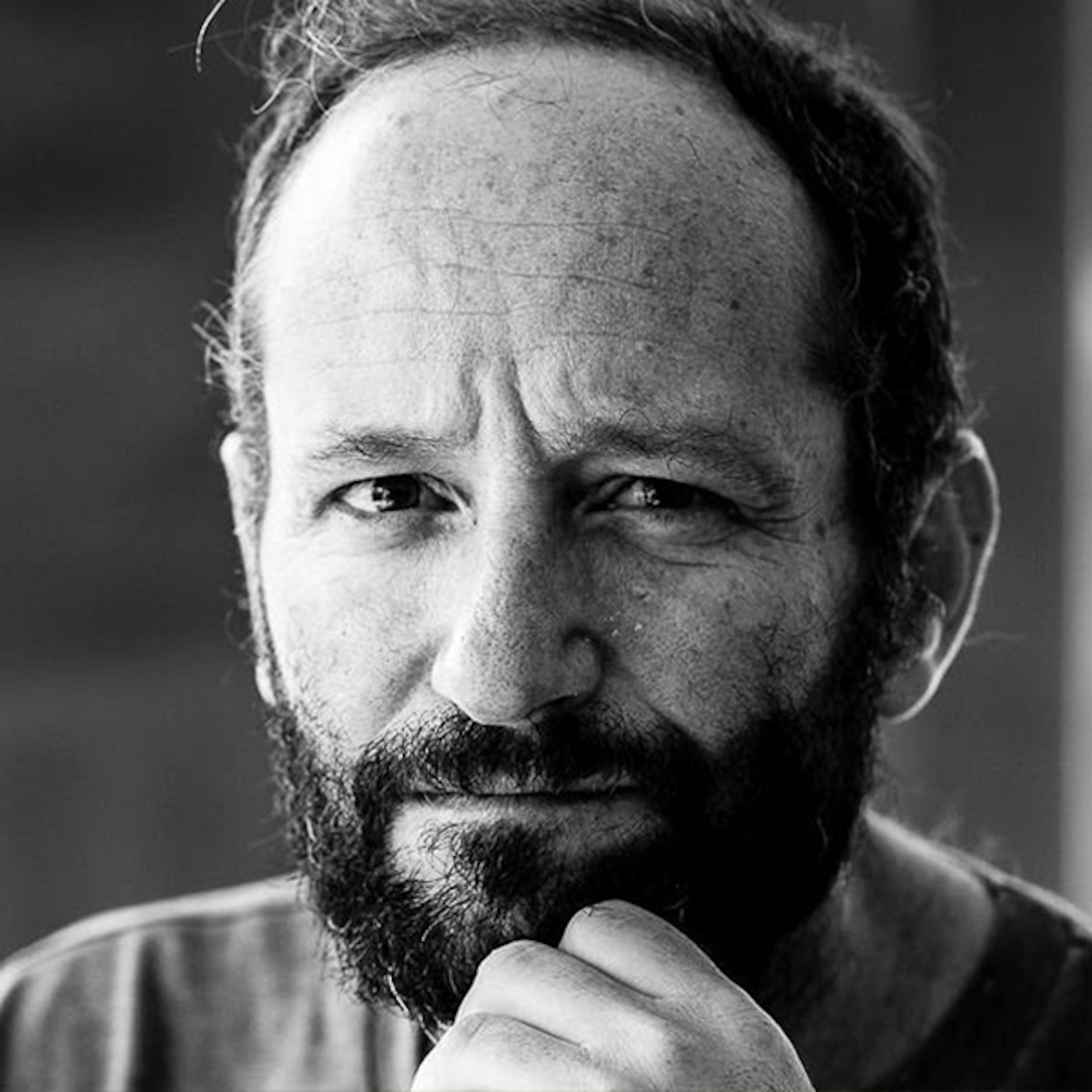 A grey and white shot of Carlos starting at the camera with a pensive look