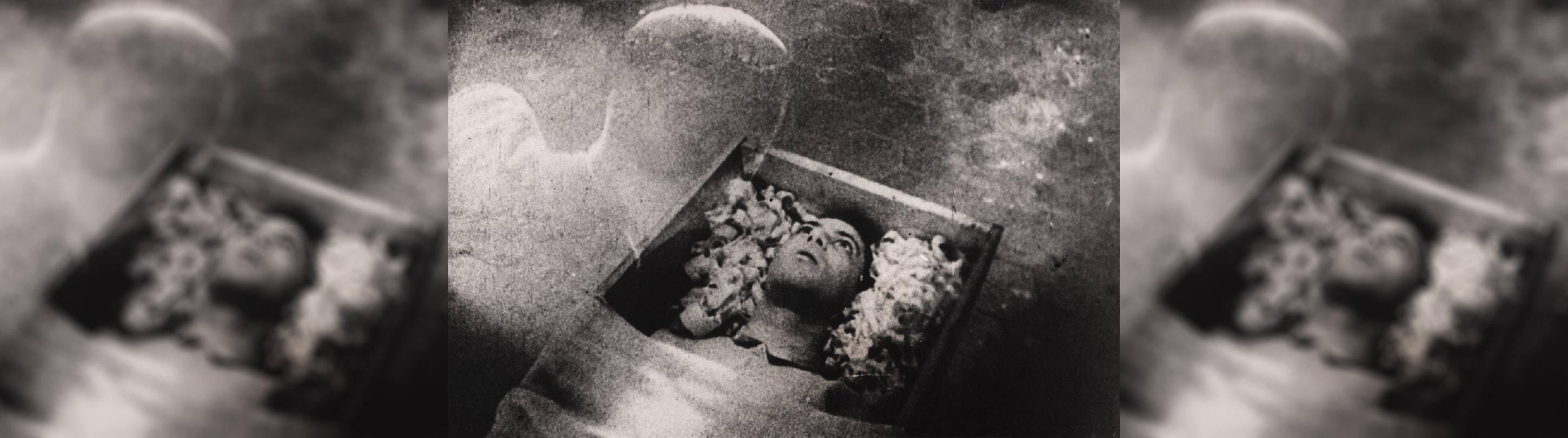A black and white image of a ghost looking into a coffin with a dead man in it