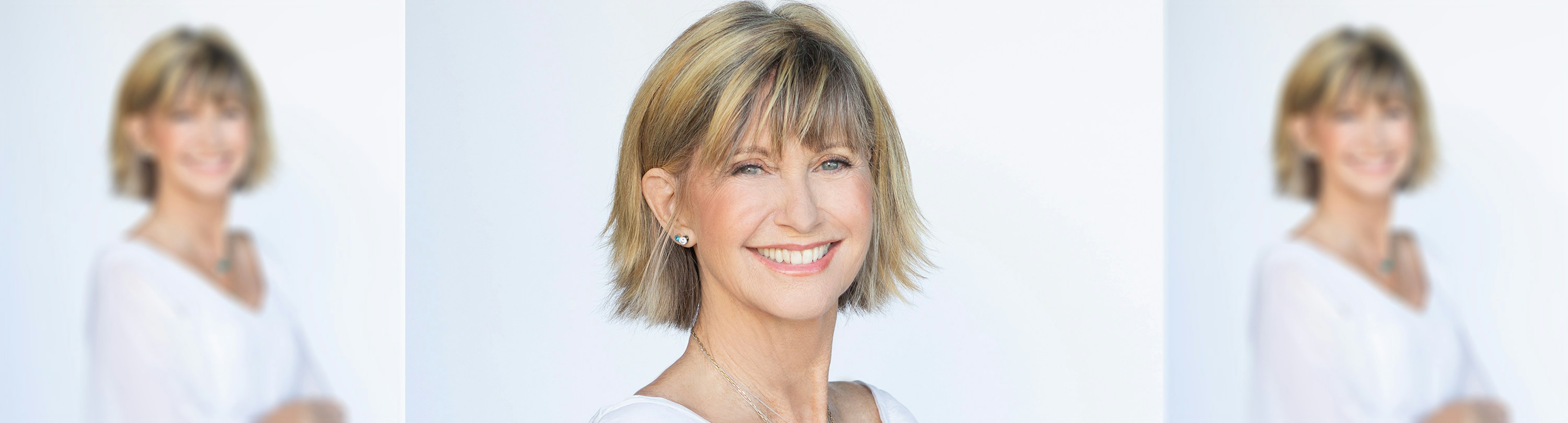 A portrait photograph of Dame Olivia Newton-John smiling at the camera