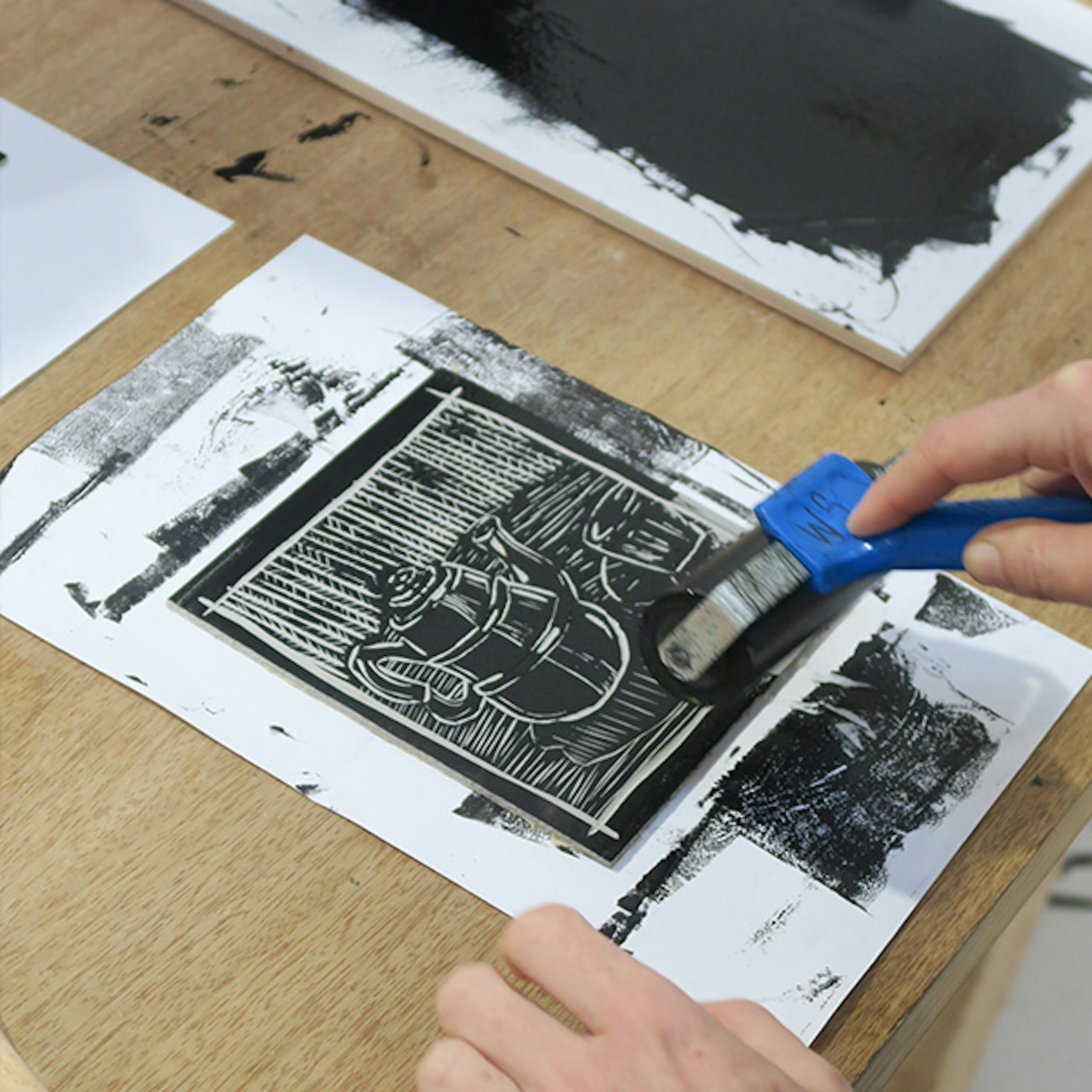 A person out of shot is using a lino cutter where they are cutting an image of a teapot