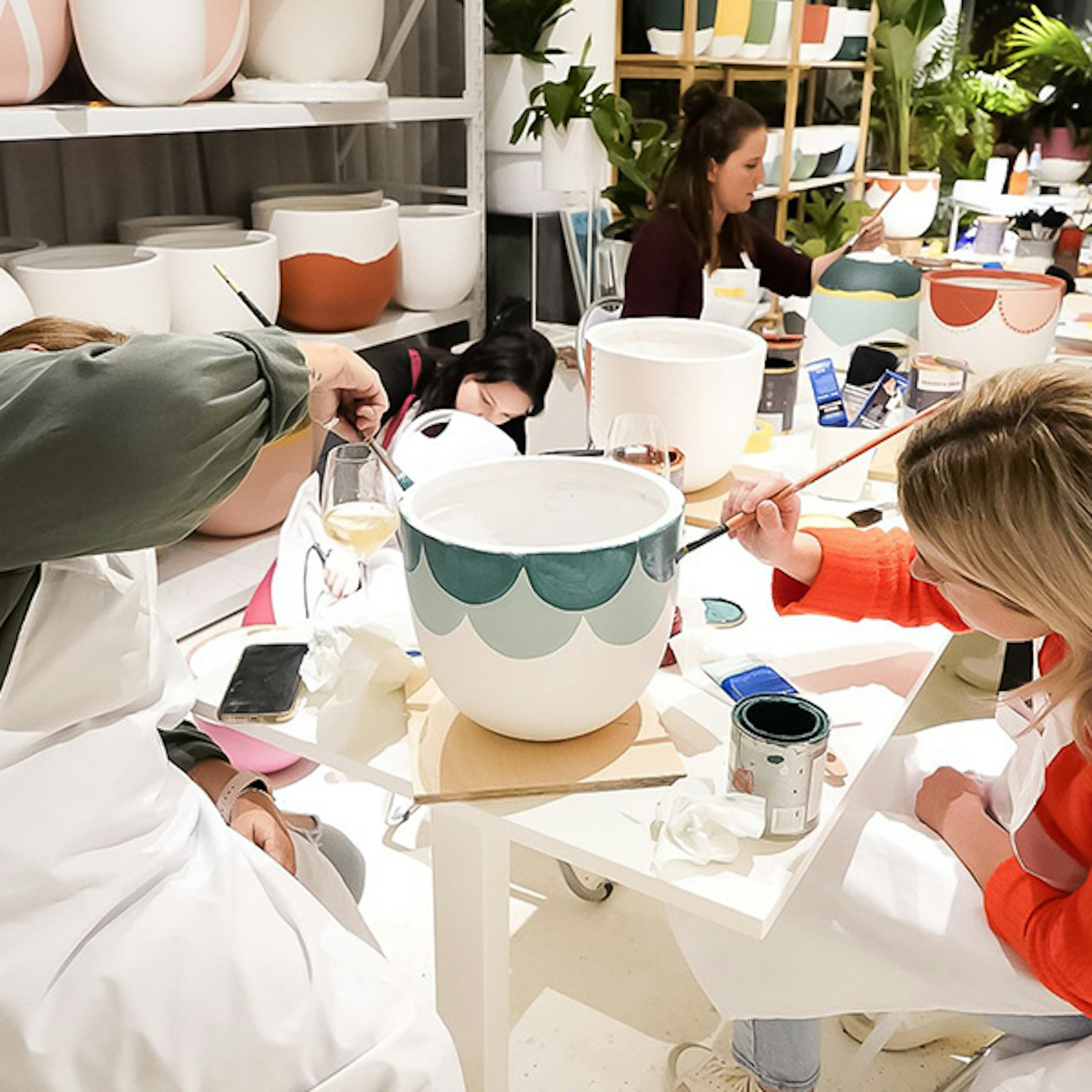 A group of people in a workshop painting pots for plants