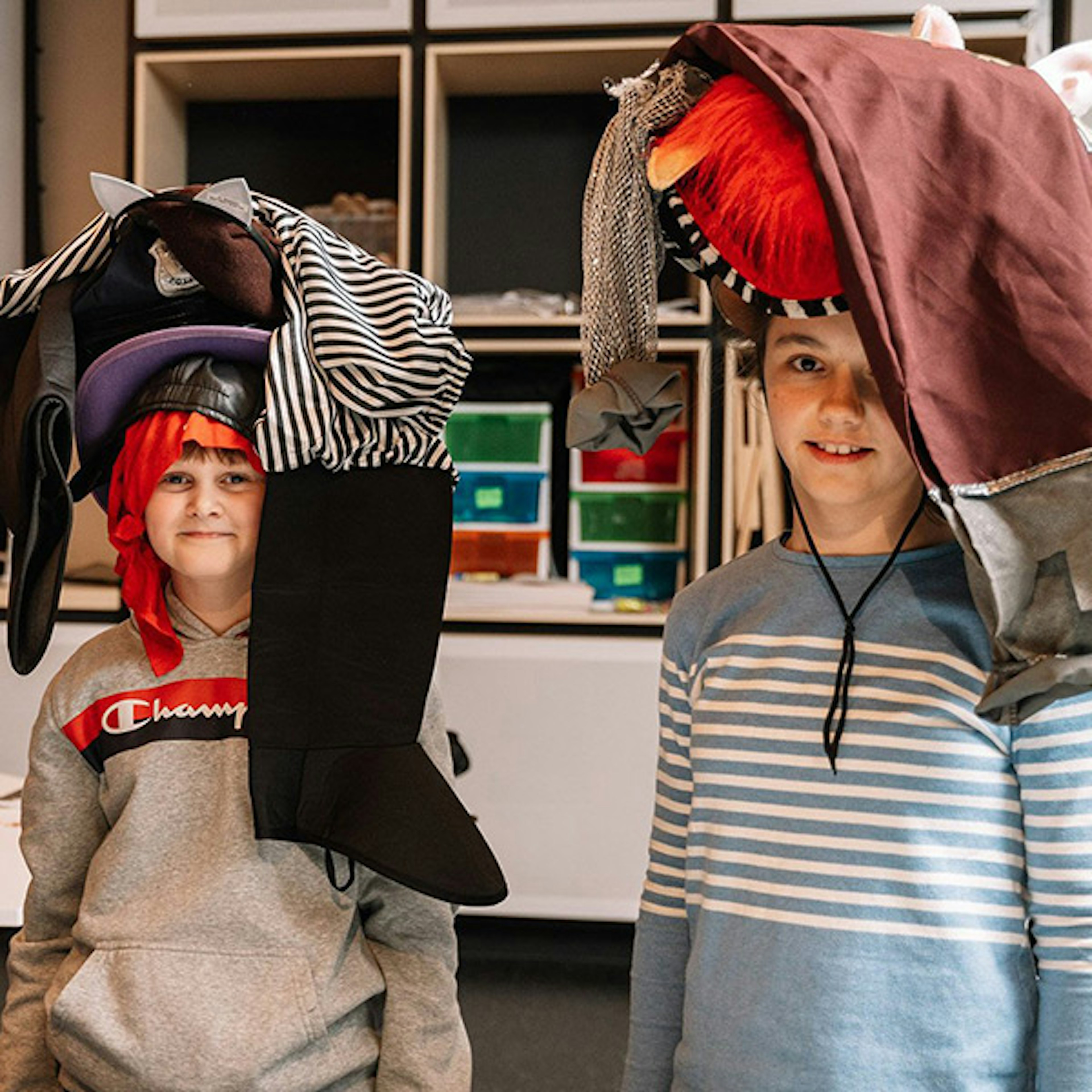 Two kids with a random assortment of clothing and item on their heads that they've created as a headdress