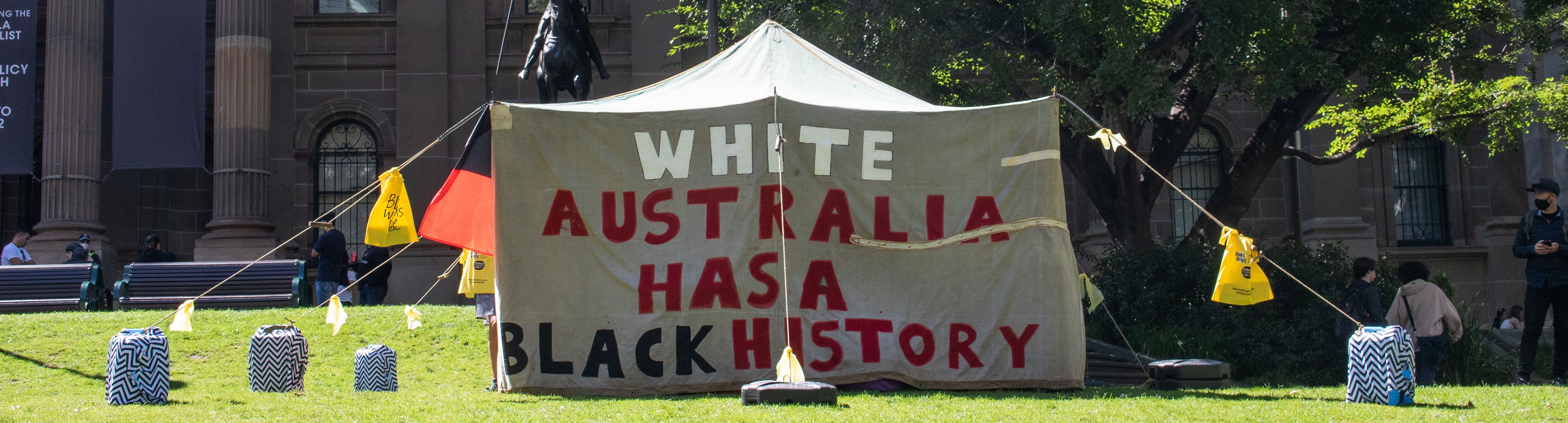 A hessian tent with the words "White Australia has a black history" painted on it
