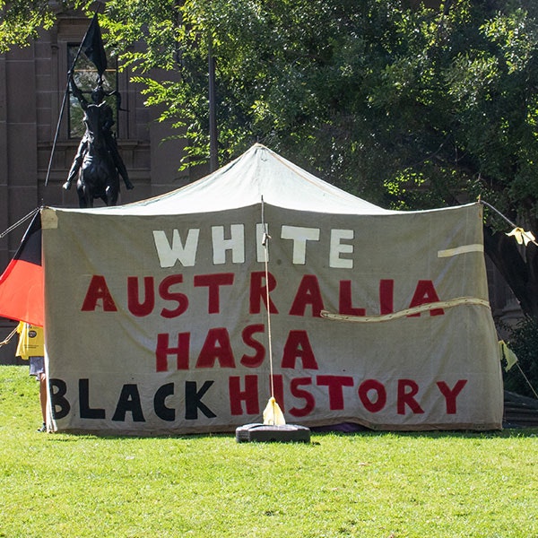 A hessian tent with the words "White Australia has a black history" painted on it