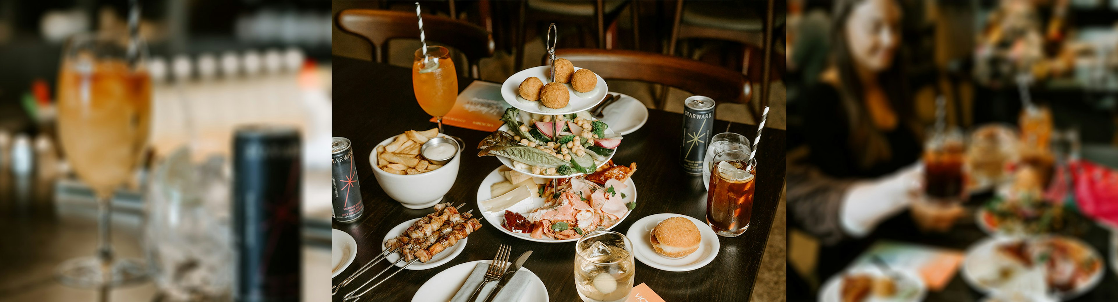 A selection of food on tiered plates with Starward Whisky premixed drinks nearby