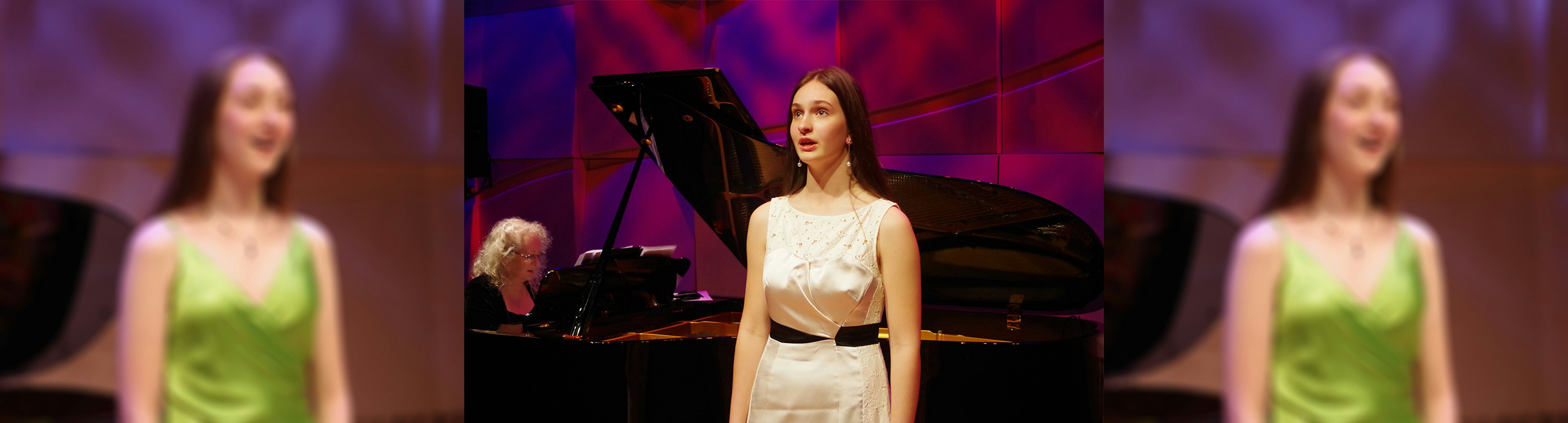 A young woman in a shiny white dress is singing in front of a grand piano