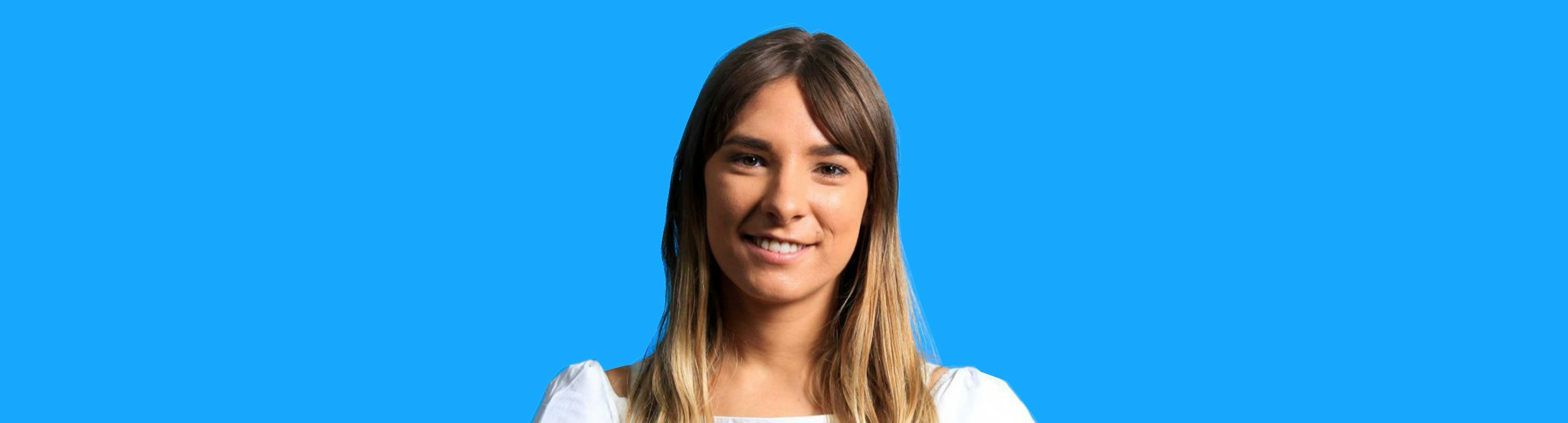 Poet Evelyn Araluen is smiling at the camera with a sky blue background behind her