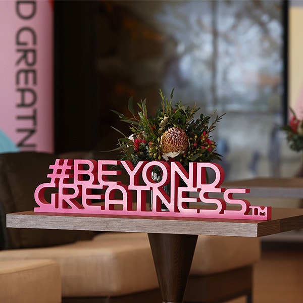 A physical pink hashtag on table that says Beyond Greatness