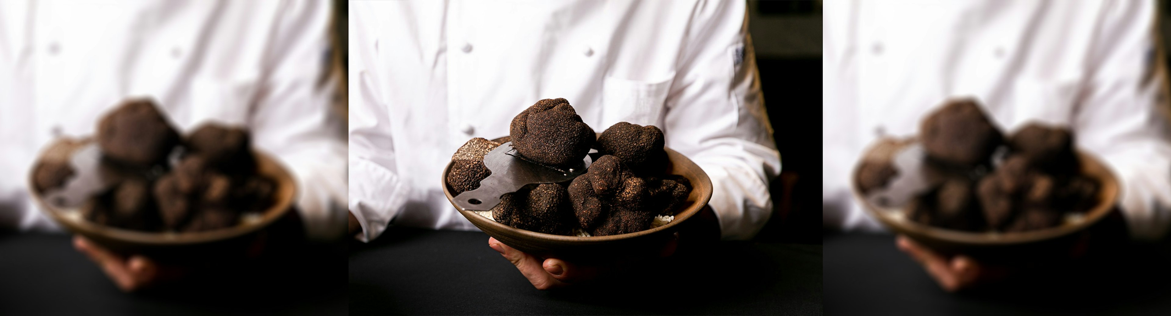 A chef wearing whites is holding a plate of truffles