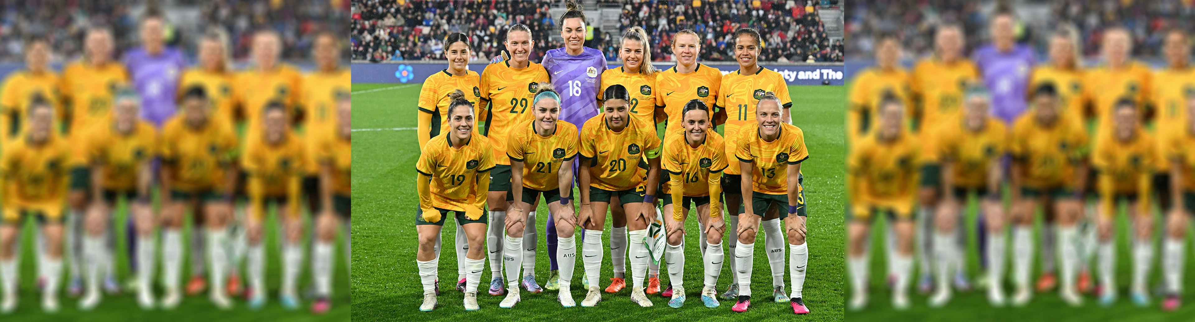 Australian women's soccer team are posing for a photo on the pitch