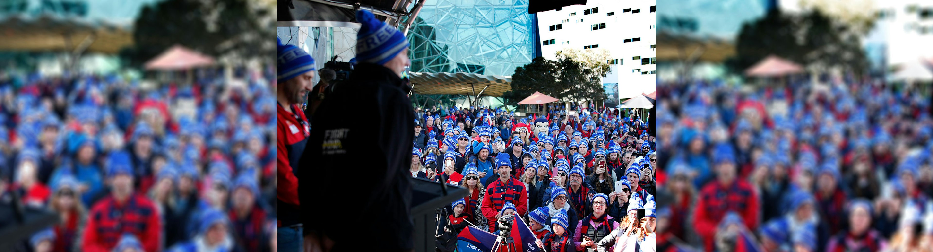 A crowd of Melbourne Football Club supporters watching Neil Daniher on stage at Fed Square