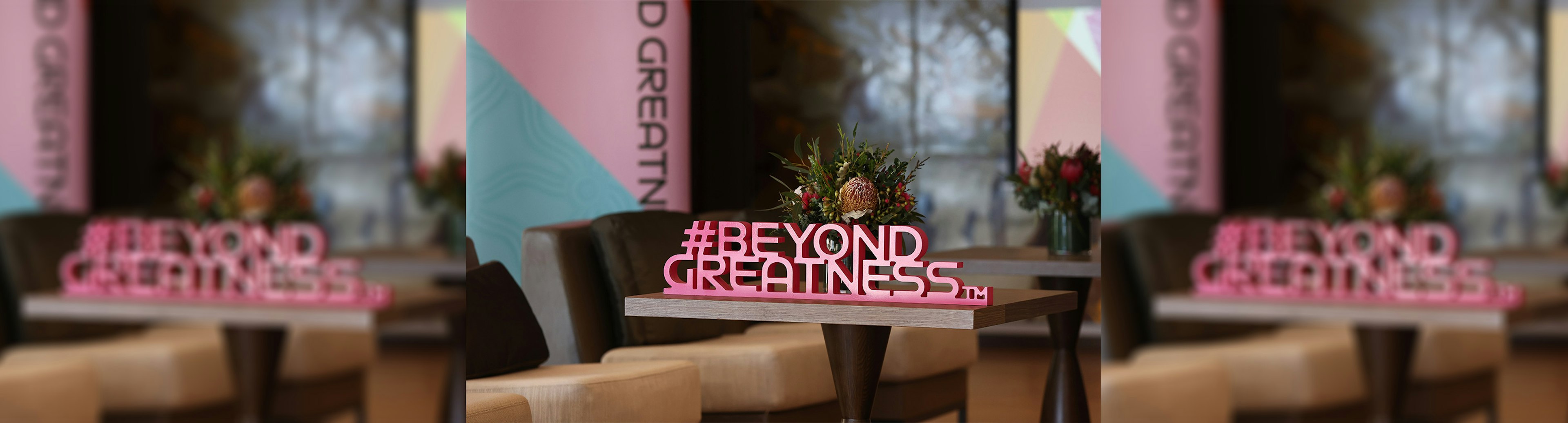 A physical pink hashtag on table that says Beyond Greatness