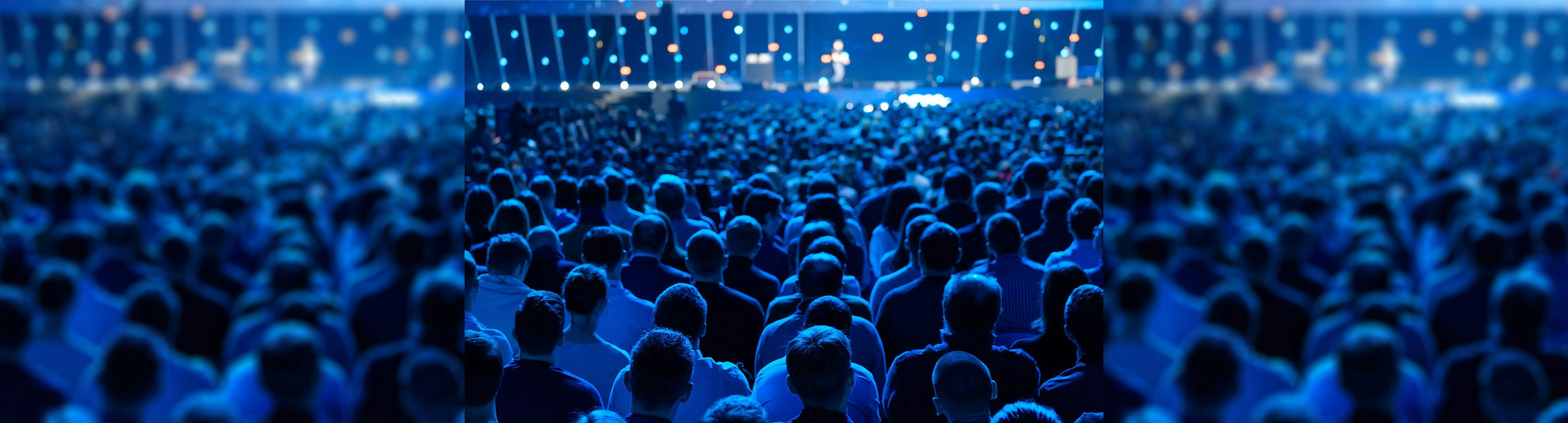 A crowd from behind watching a speaker on stage