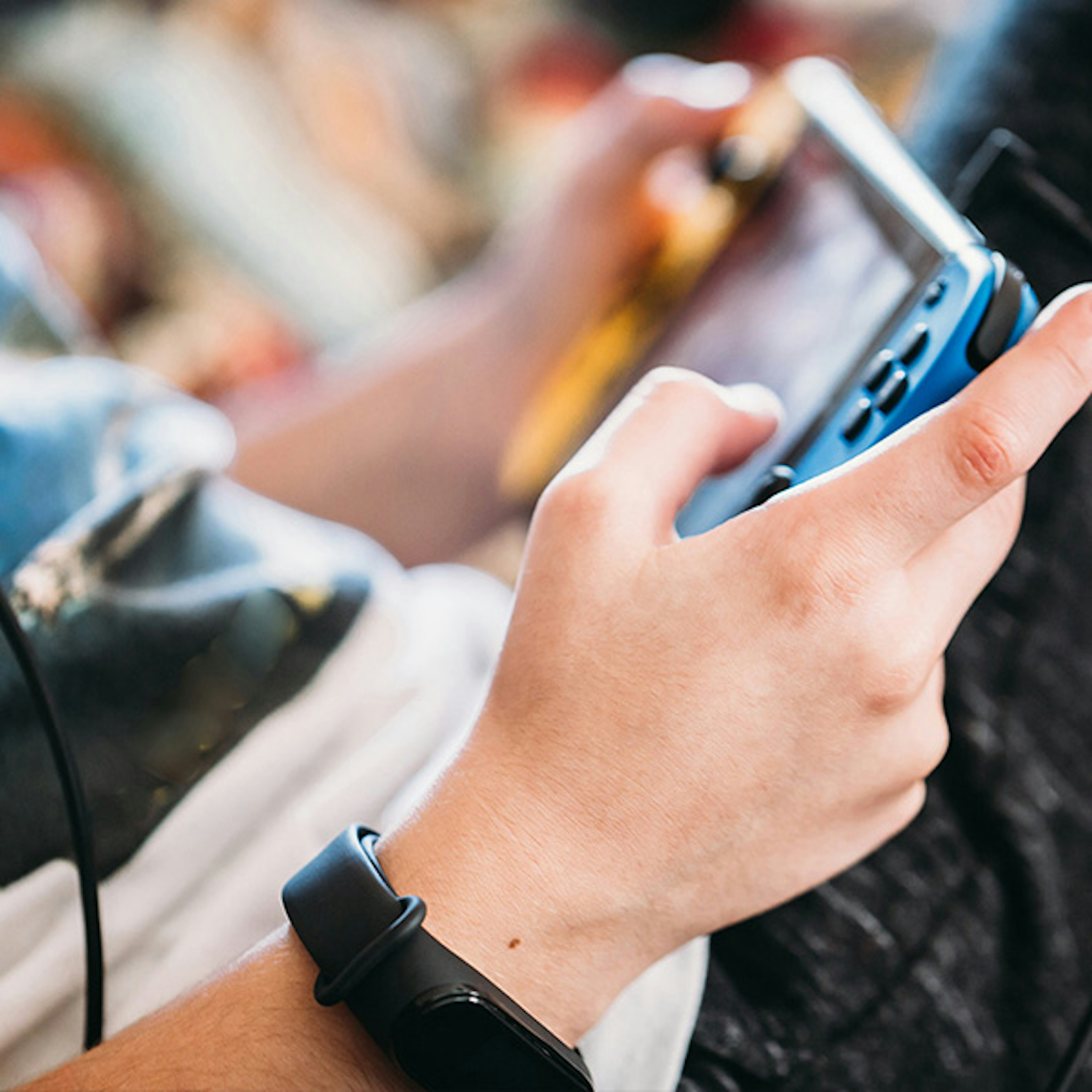 A photo focused on the torso of a boy sitting down and playing a Nintendo Switch with the Switch resting on his leg