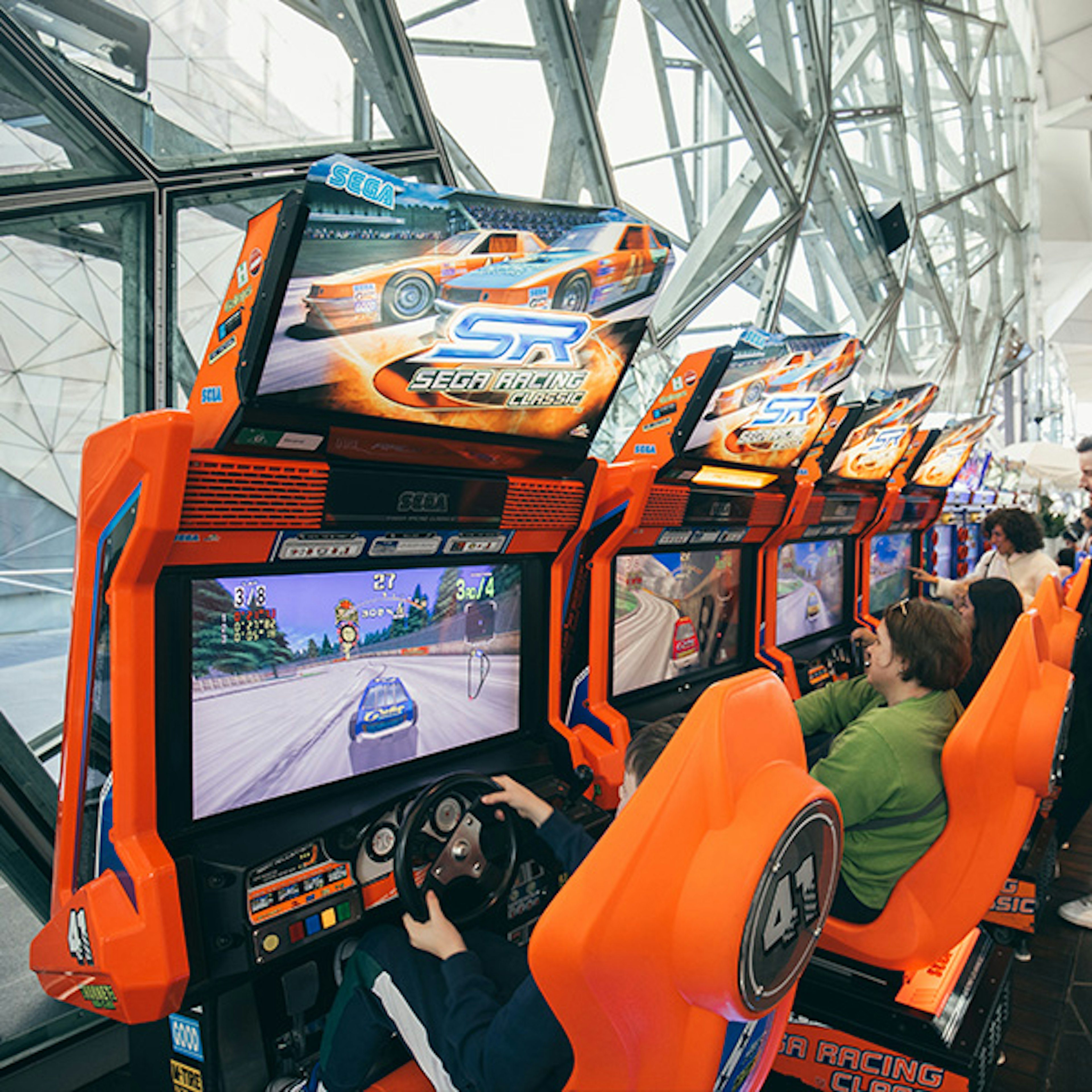 People playing arcade racing games in The Edge