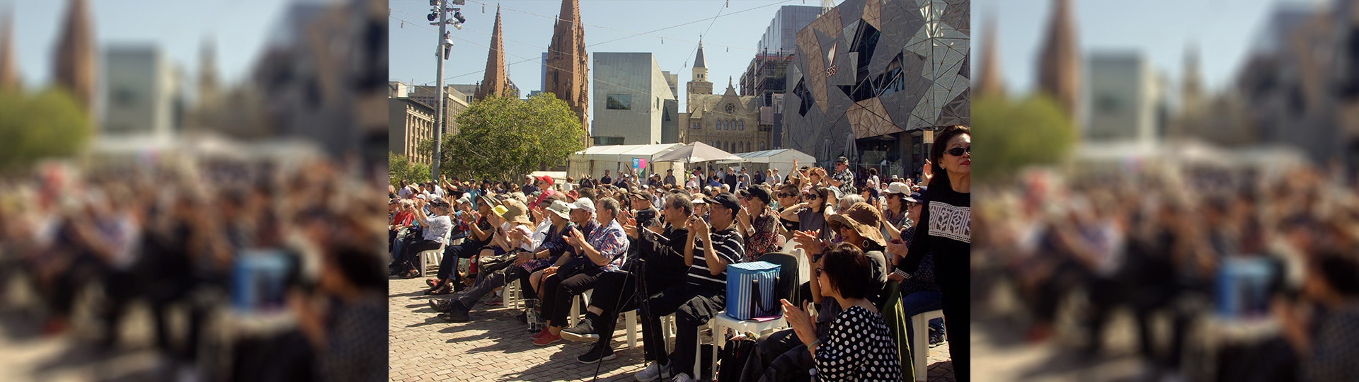 A crowd of seniors sitting down watching the main stage at Fed Square