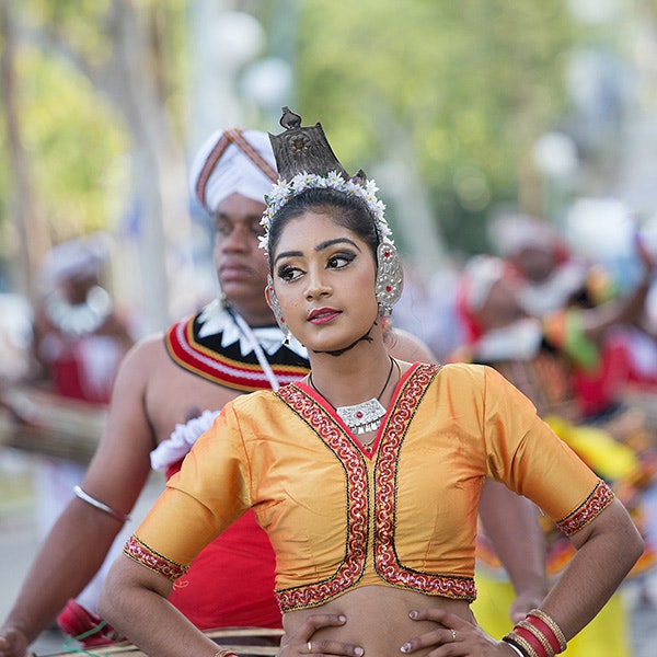 A Sri Lankan women in orange traditional fashion, mid pose while dancing
