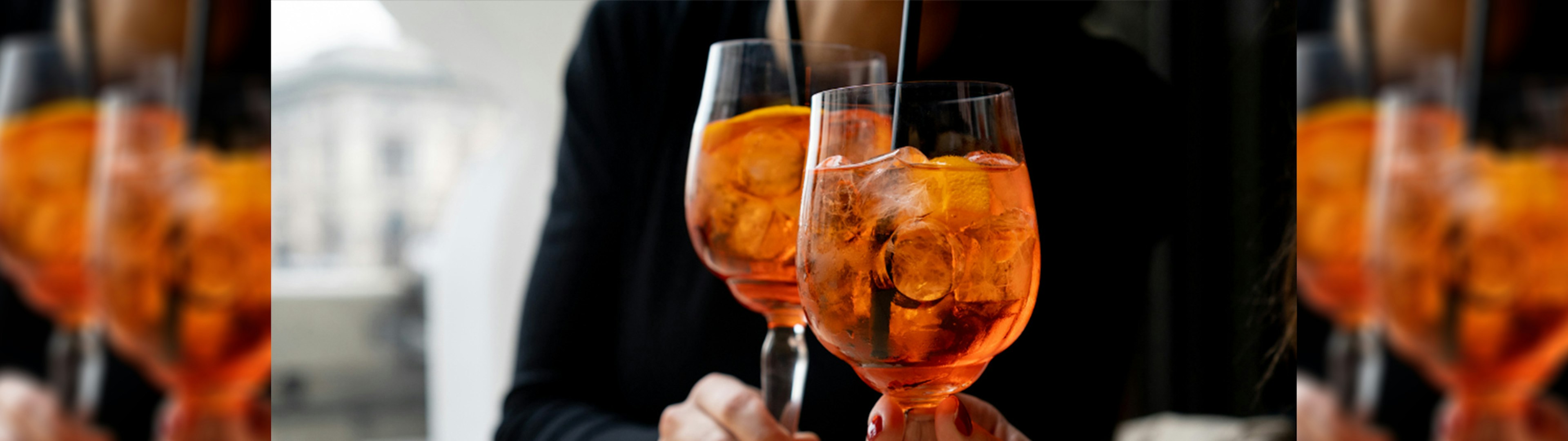 A close up photo of two Aperol spritz cocktails cheersing