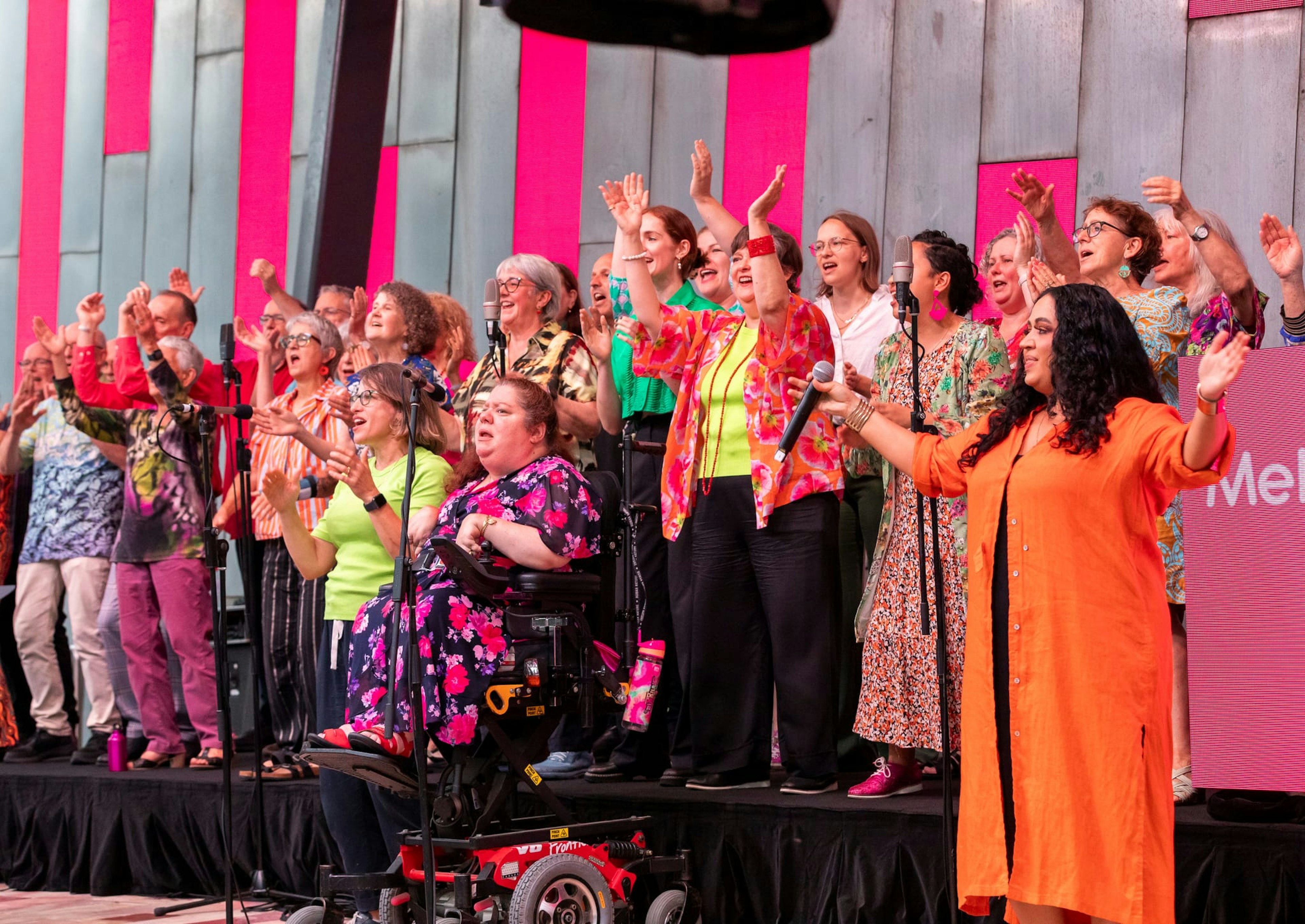 A group of colourfully-dressed choralists perform at Fed Square.