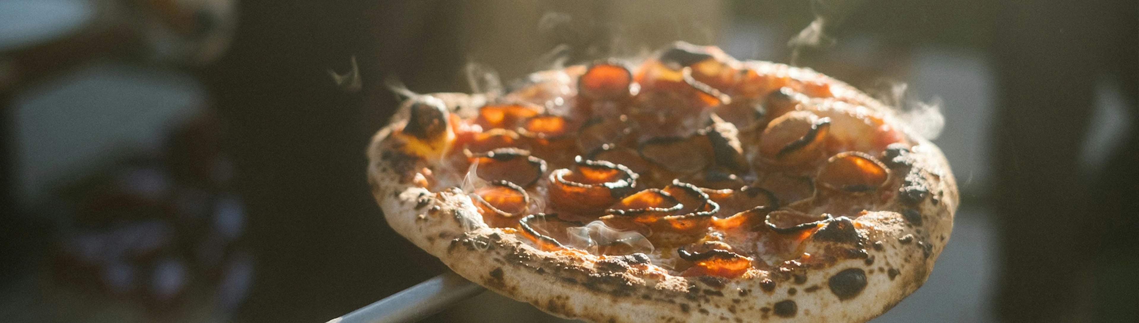 A close up of pepperoni pizza steaming as it has just come out of the oven