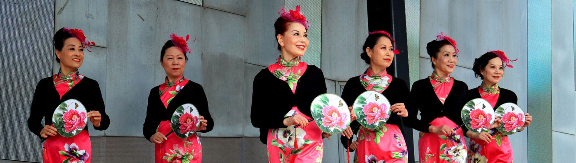 Six Chinese women dressed in traditonal clothing on stage at Fed Square dancing