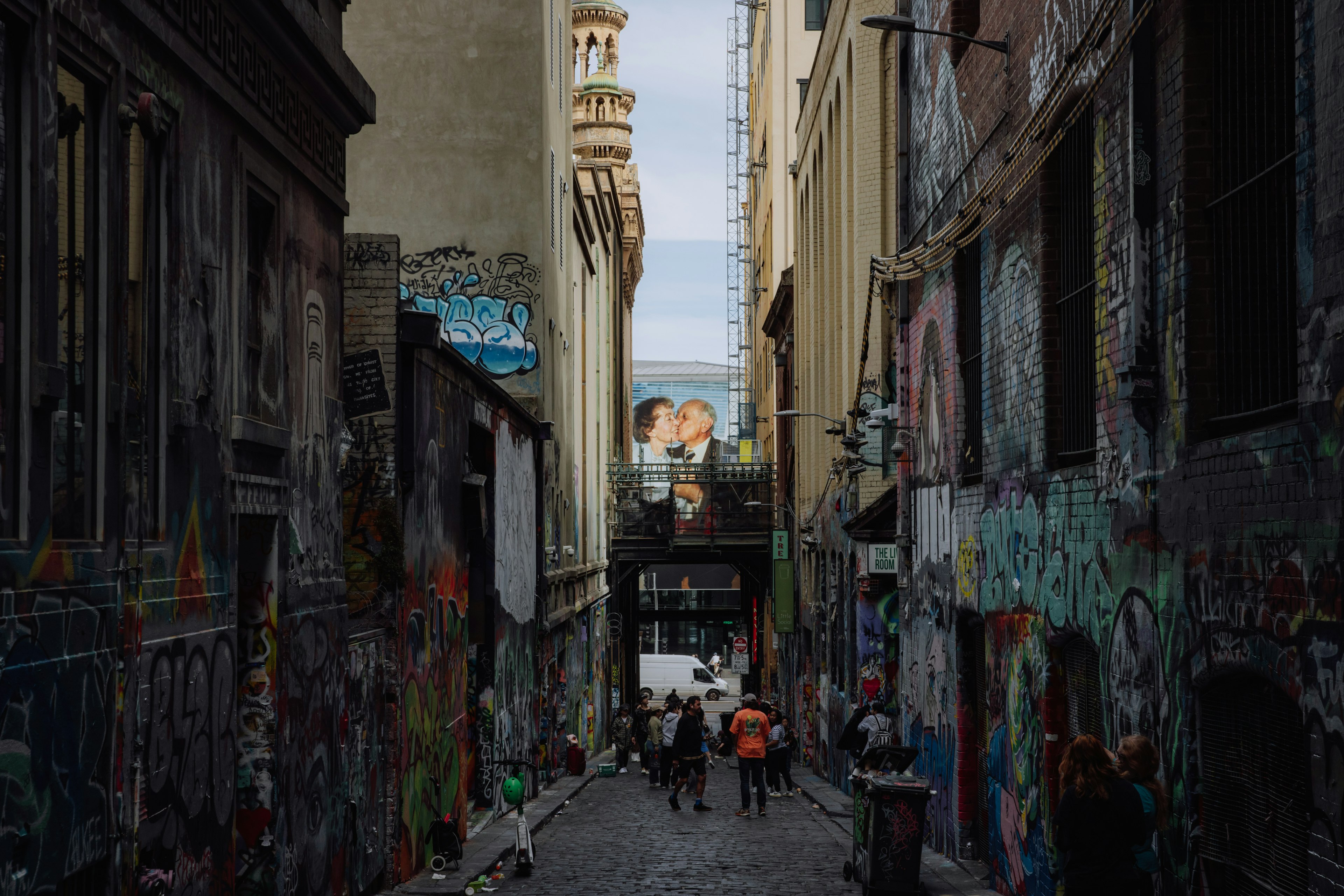 Through the narrow gap between buildings, from up Hosier Lane, we see the faces of an elderly couple - a photographic installation of the artist's parents in 1989. The man kisses the woman on the cheek. They are dressed up.