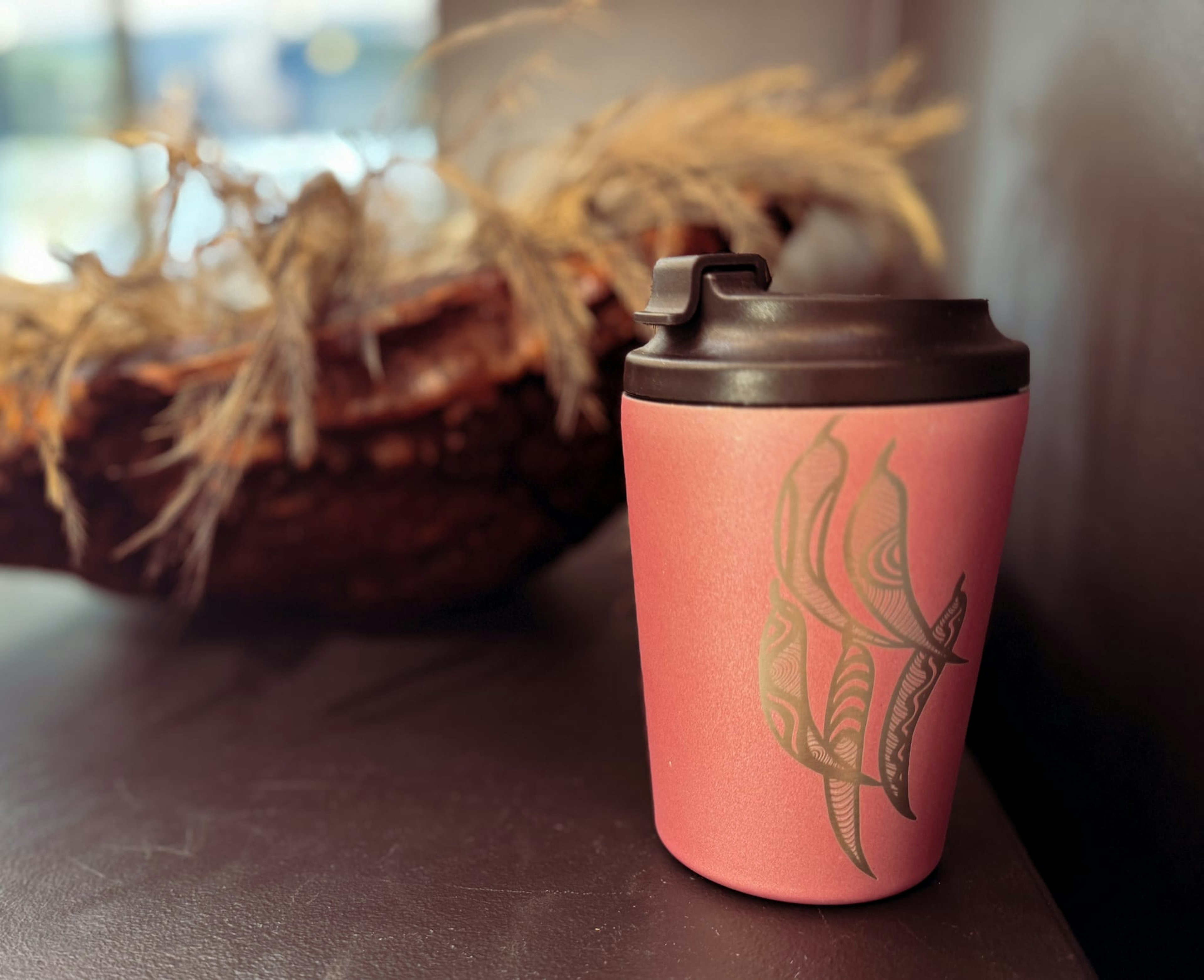 A pink insulated mug, with a leaf design.