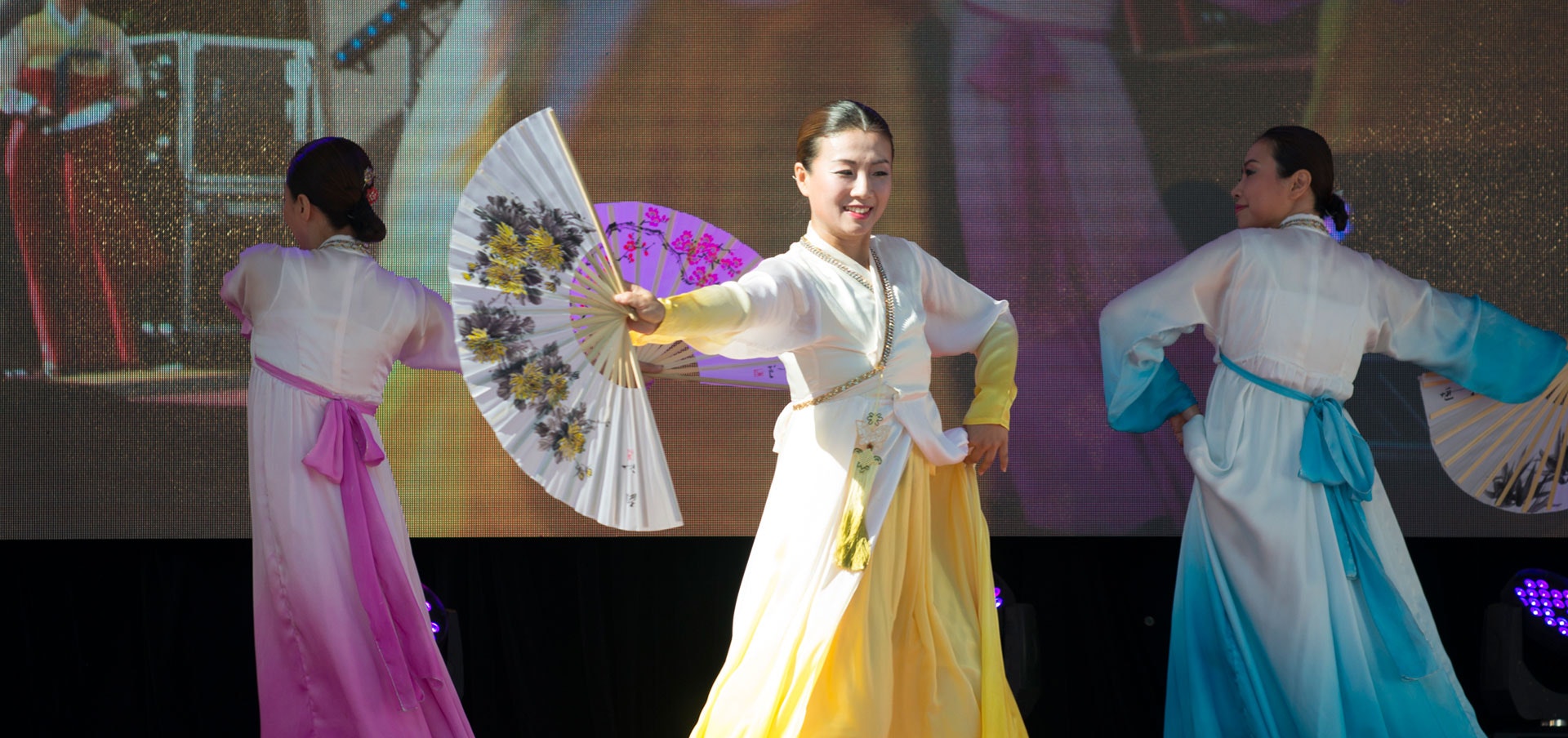 Traditional Korean dancers holding hand fans while performing on stage at Fed Square