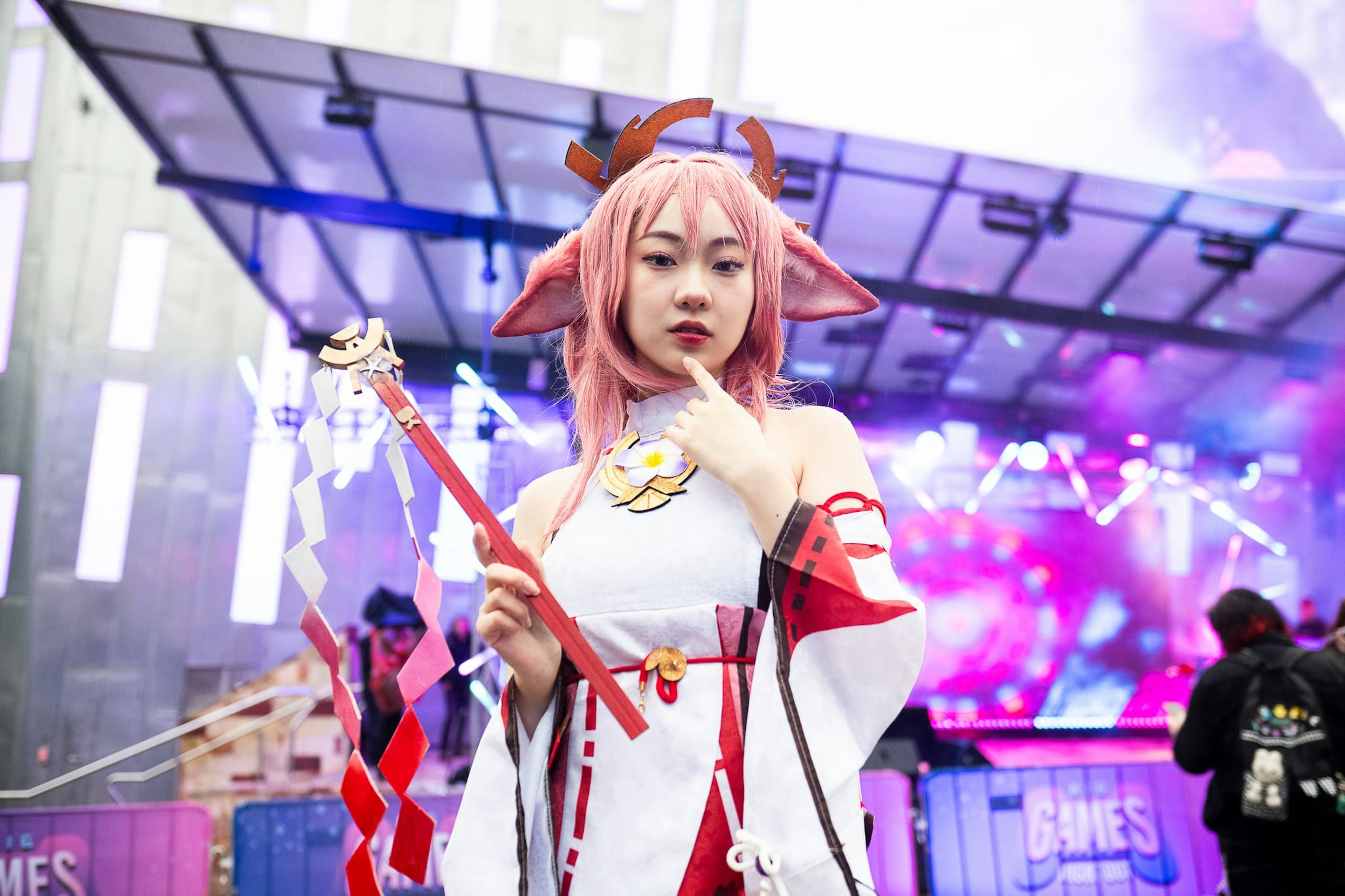 Woman in cosplay in front of the Fed Square stage. She has pink hair, elven ears and wears a white tunic.