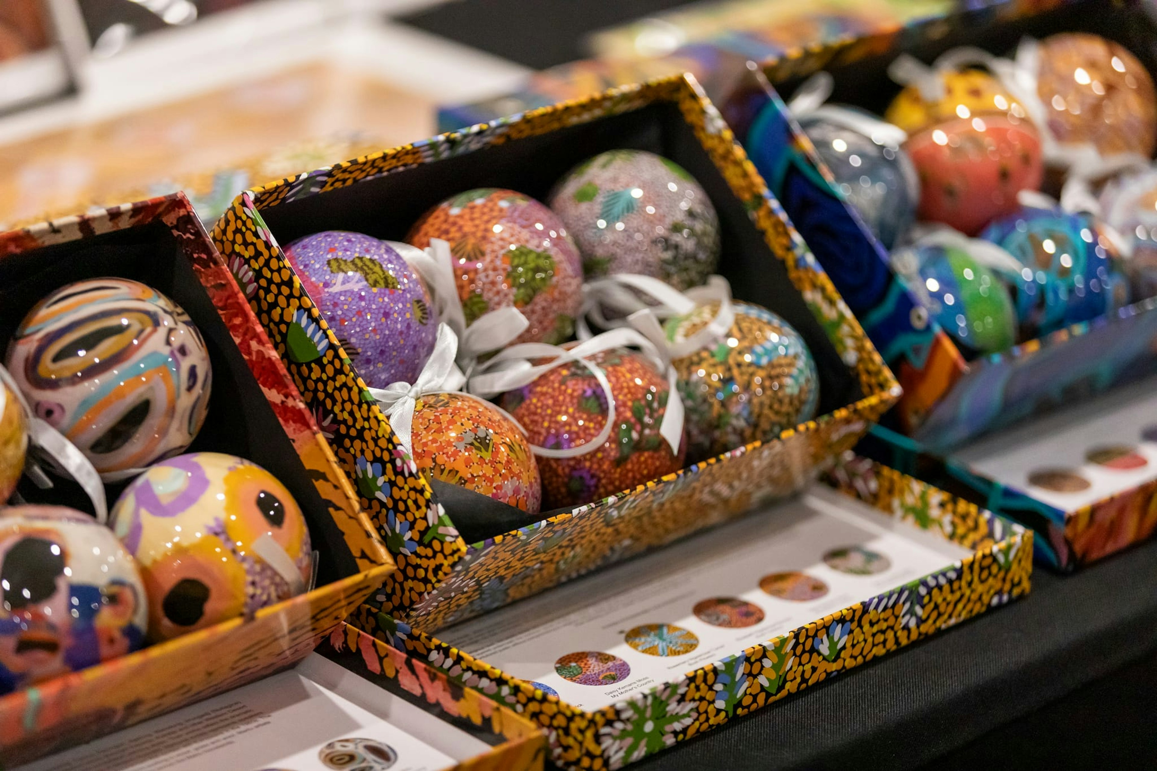 Colourful round Christmas baubles in a container of six, featuring First Peoples' designs