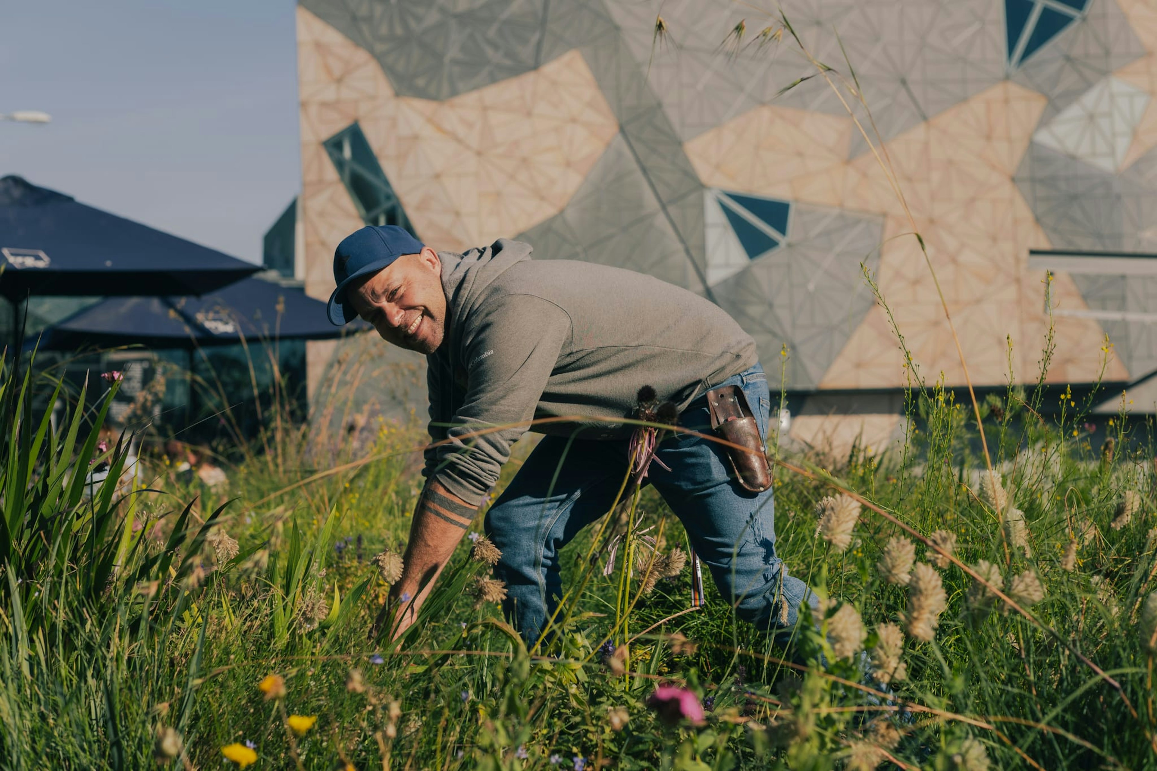 A man pulls weeds in the Test Garden at Fed Square.