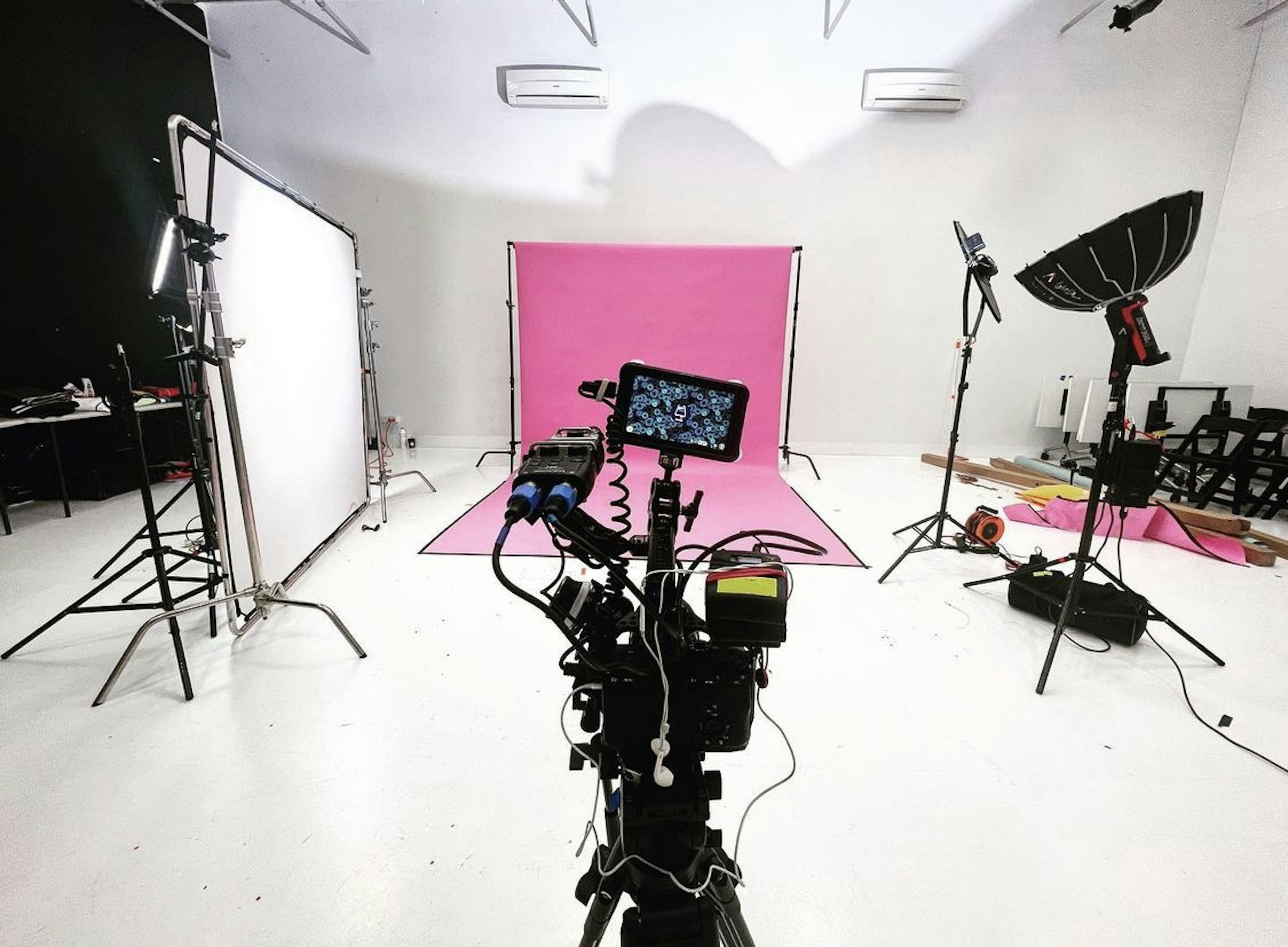 A studio set up with cameras and lights and a pink back drop